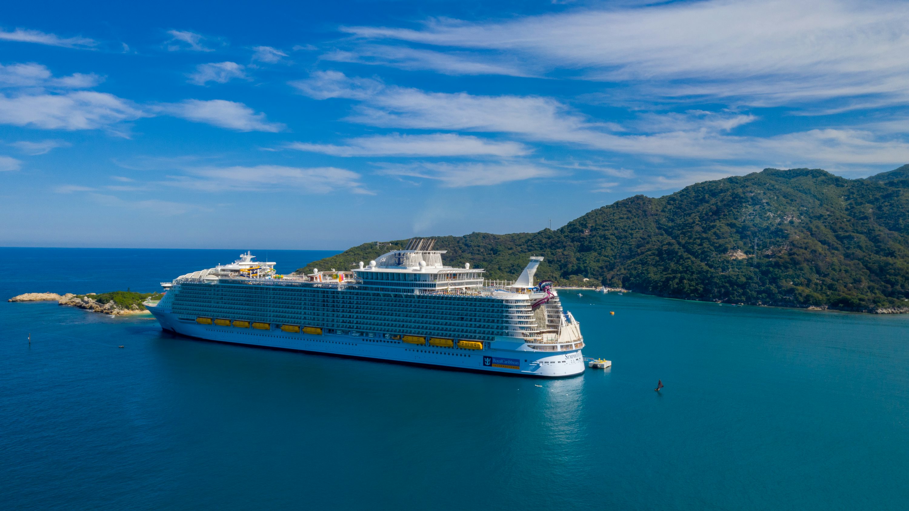 Cruise ship sailing beside a green tropical island